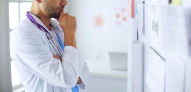 Genç ve kendinden emin erkek doktor portresi tıp ofisinde duruyor..