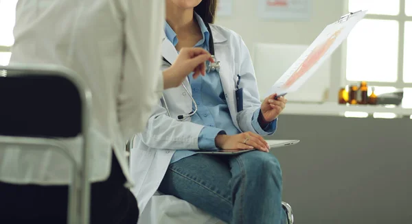 Arzt und Patient diskutieren etwas, während sie am Tisch sitzen. Medizin und Gesundheitskonzept — Stockfoto