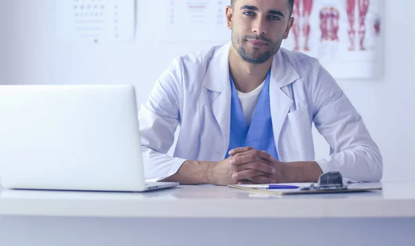 Retrato de un médico varón con portátil sentado en el escritorio en el consultorio médico. — Foto de Stock