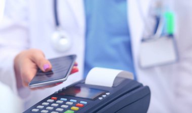 Doktor ödeme terminalini elinde tutuyor. Sağlık hizmetlerinin parasını ödüyorum. Doktor.