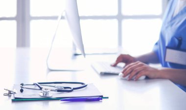 Masada oturan gülümseyen güzel genç bayan doktor.