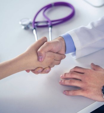 Doktor masadaki hastaya el sıkışıyor.