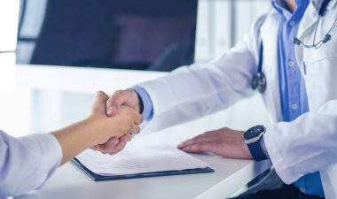 Doktor masadaki hastaya el sıkışıyor.