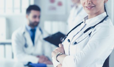 Steteskoplu kadın doktor kolları bağlı duruyor.