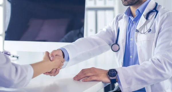 Doctor estrechando la mano al paciente en la oficina en el escritorio —  Fotos de Stock