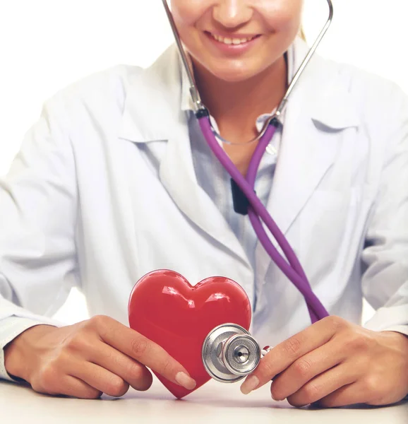 Female doctor with stethoscope holding heart, on light background — Stock Photo, Image