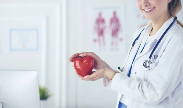 Kvinna läkare med stetoskop hålla hjärtat, på ljus bakgrund — Stockfoto