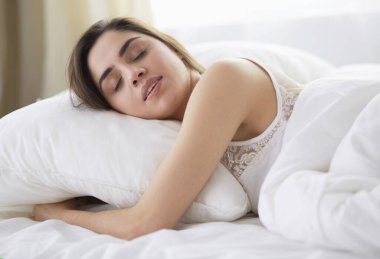 Güzel bir kadın yatağında uzanıyor.