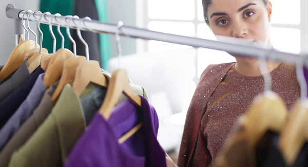 Mooie jonge stylist bij rek met hangers — Stockfoto