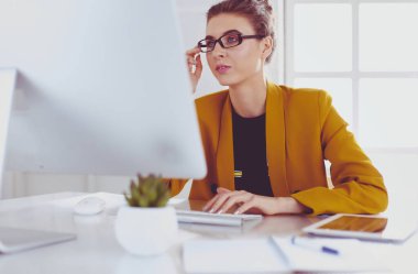 Ofis masasında çalışan ve dizüstü bilgisayarla yazan kendine güvenen genç bir iş kadını.