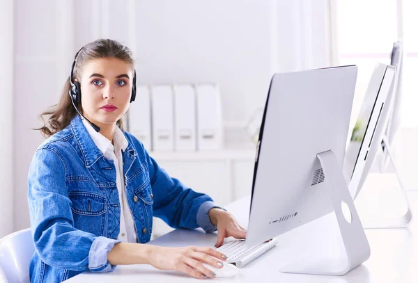 Retrato de mulher de negócios bonita trabalhando em sua mesa com fone de ouvido e laptop — Fotografia de Stock