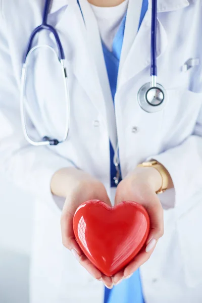 Kvinna läkare med stetoskop hålla hjärtat, på ljus bakgrund — Stockfoto