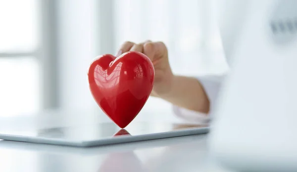 Doctora con estetoscopio sosteniendo el corazón, sobre fondo claro —  Fotos de Stock