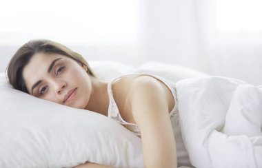Güzel bir kadın yatağında uzanıyor.