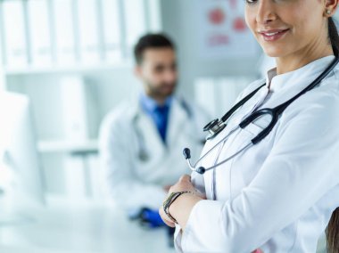 Steteskoplu kadın doktor kolları bağlı duruyor.
