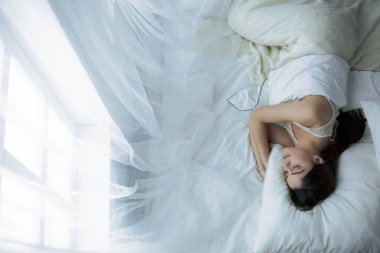 Güzel bir kadın yatağında uzanıyor.