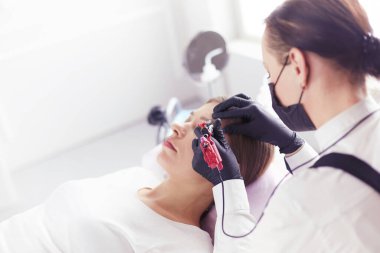 Güzellik salonunda kaş makyajı yapılan genç bir kadın.