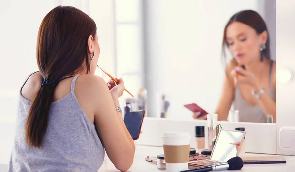 Junge Frau trägt Lippenstift vor dem Spiegel auf — Stockfoto