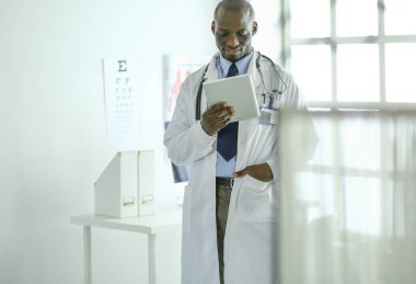 Tablet bilgisayarlı siyahi bir doktor hastanede bekliyor.