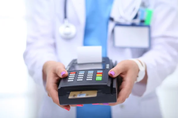 Doktor trzyma terminal płatniczy w rękach. Płacenie za opiekę zdrowotną. Doktorze. — Zdjęcie stockowe
