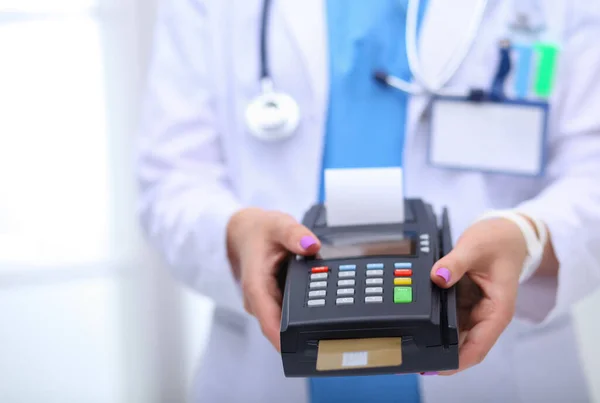 De dokter houdt de betaalterminal in handen. Betalen voor de gezondheidszorg. Dokter. — Stockfoto