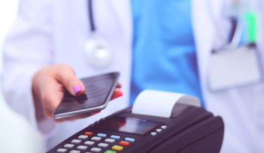 Doktor ödeme terminalini elinde tutuyor. Sağlık hizmetlerinin parasını ödüyorum. Doktor.