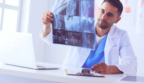 Beau médecin parle avec une jeune patiente et prend des notes alors qu'il est assis dans son bureau. — Photo