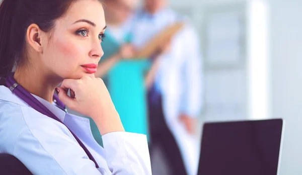 Hermosa joven sonriente doctora sentada en el escritorio — Foto de Stock