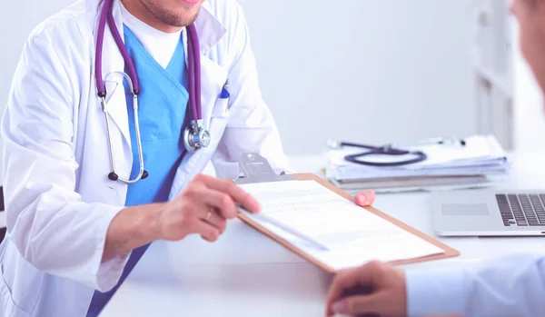 Retrato de un médico varón sonriente con portátil sentado en el escritorio en el consultorio médico — Foto de Stock