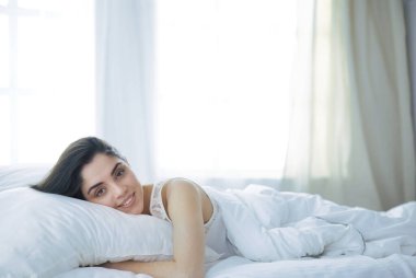 Güzel bir kadın yatağında uzanıyor.