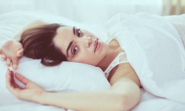 Güzel bir kadın yatağında uzanıyor.