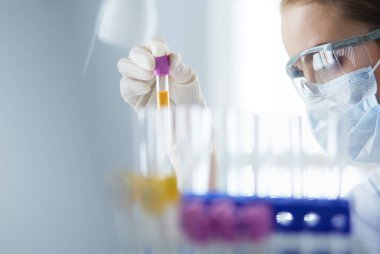 Laboratuvarda sıvı yeşil çözeltiye bakan bir tıbbi veya bilimsel araştırmacı ya da doktor