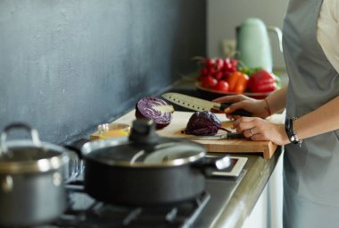 Masanın yanında duran mutfakta sebze doğrayan genç bir kadın.