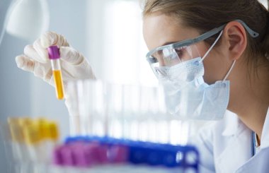 Laboratuvarda sıvı yeşil çözeltiye bakan bir tıbbi veya bilimsel araştırmacı ya da doktor