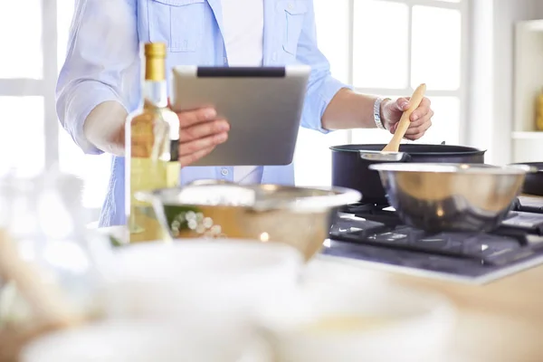 Man following recipe on digital tablet and cooking tasty and healthy food in kitchen at home — Stock Photo, Image
