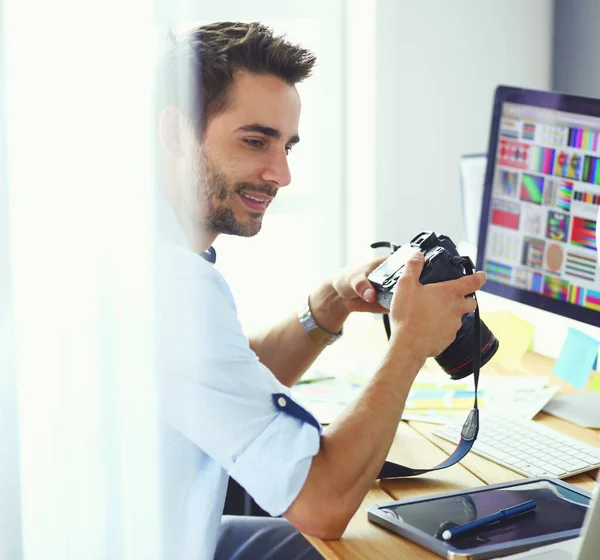 Retrato de jovem designer sentado no estúdio gráfico na frente de laptop e computador enquanto trabalhava online. — Fotografia de Stock