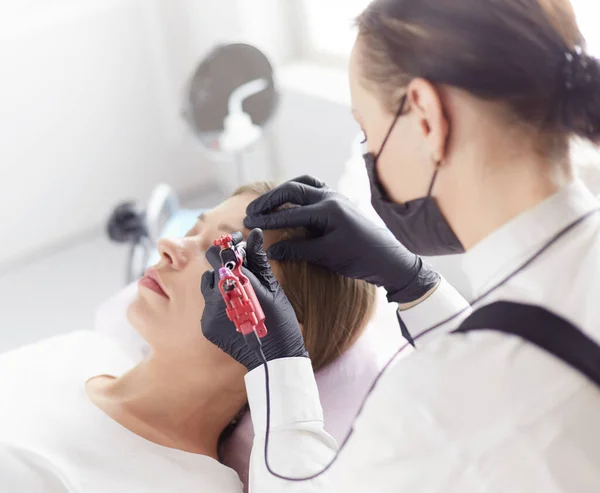 Young woman undergoing procedure of eyebrow permanent makeup in beauty salon — Stock Photo, Image