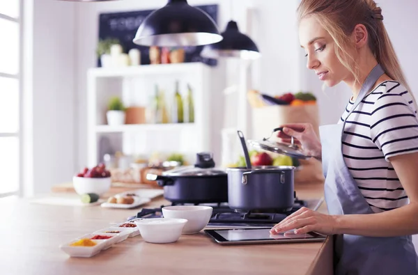 Mujer joven usando una tableta para cocinar en su cocina —  Fotos de Stock