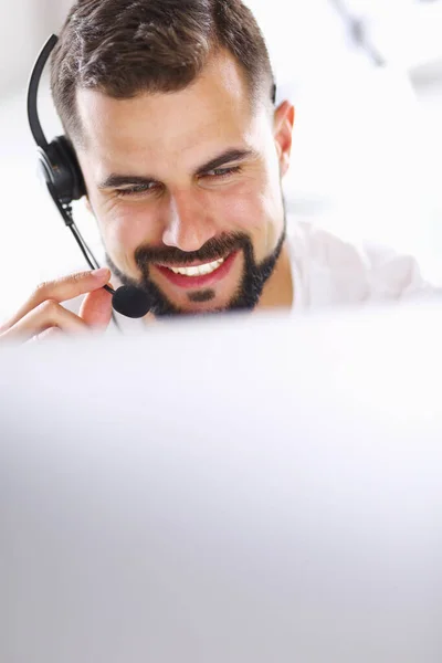 Retrato de un joven con un auricular frente a una computadora portátil — Foto de Stock