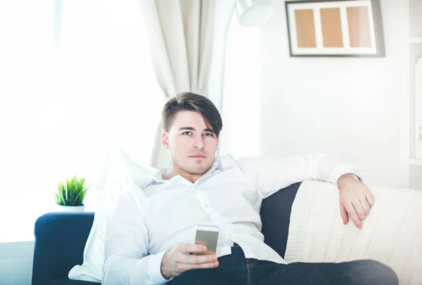 Handsome young man using smartphone at home — Stock Photo, Image