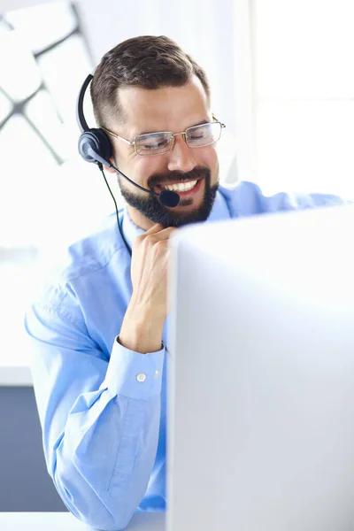 Retrato de un joven con un auricular frente a una computadora portátil —  Fotos de Stock