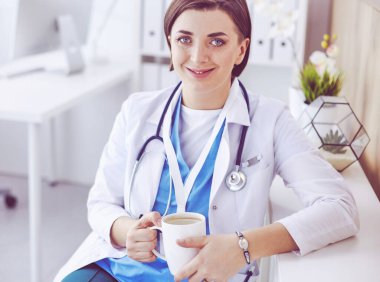 Elinde kahve tutan profesyonel kadın doktorun portresi.