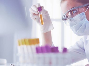 Modern laboratuvar veya hastanede plastik tıbbi tüplerle çalışan araştırmacı, doktor, bilim adamı veya laboratuvar asistanı