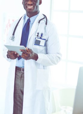 Tablet bilgisayarlı siyahi bir doktor hastanede bekliyor.