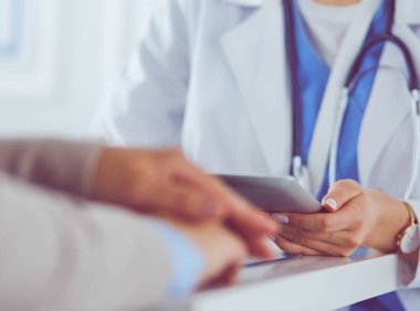 Kadın doktor hastane lobisinde tablet bilgisayar kullanarak, gülümseyerek