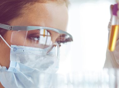 Modern laboratuvar veya hastanede plastik tıbbi tüplerle çalışan araştırmacı, doktor, bilim adamı veya laboratuvar asistanı