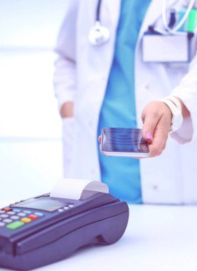 Doktor ödeme terminalini elinde tutuyor. Sağlık hizmetlerinin parasını ödüyorum. Doktor.