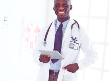 Tablet bilgisayarlı siyahi bir doktor hastanede bekliyor.