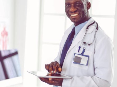 Tablet bilgisayarlı siyahi bir doktor hastanede bekliyor.