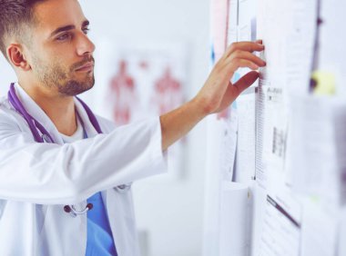 Genç ve kendinden emin erkek doktor portresi tıp ofisinde duruyor.